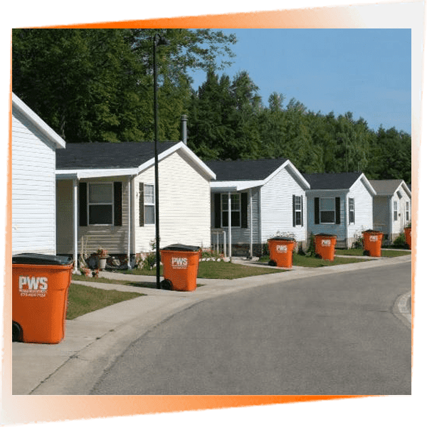 Row of white postal service buildings with orange mail bins outside.